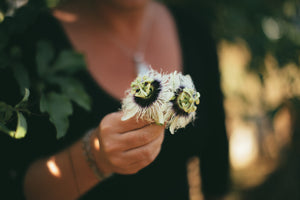 woman wearing moonstone holding lilikoi, or passion flowers